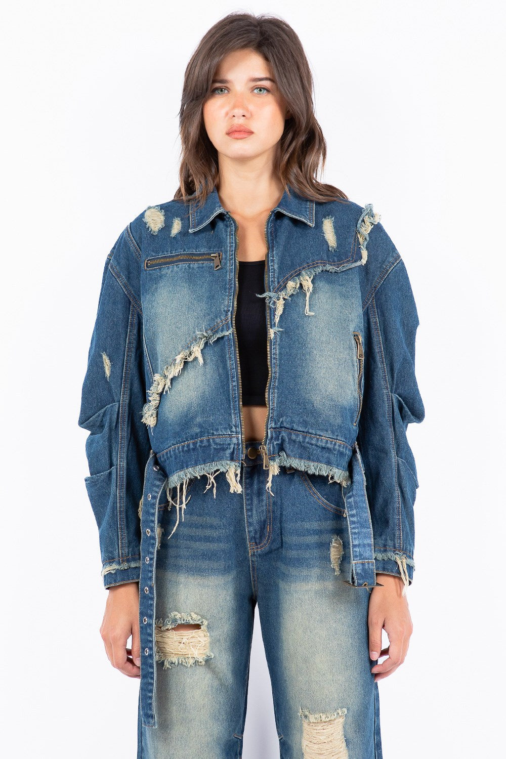 Woman wearing a distressed frayed medium wash denim jacket and jeans streetwear style on a white background