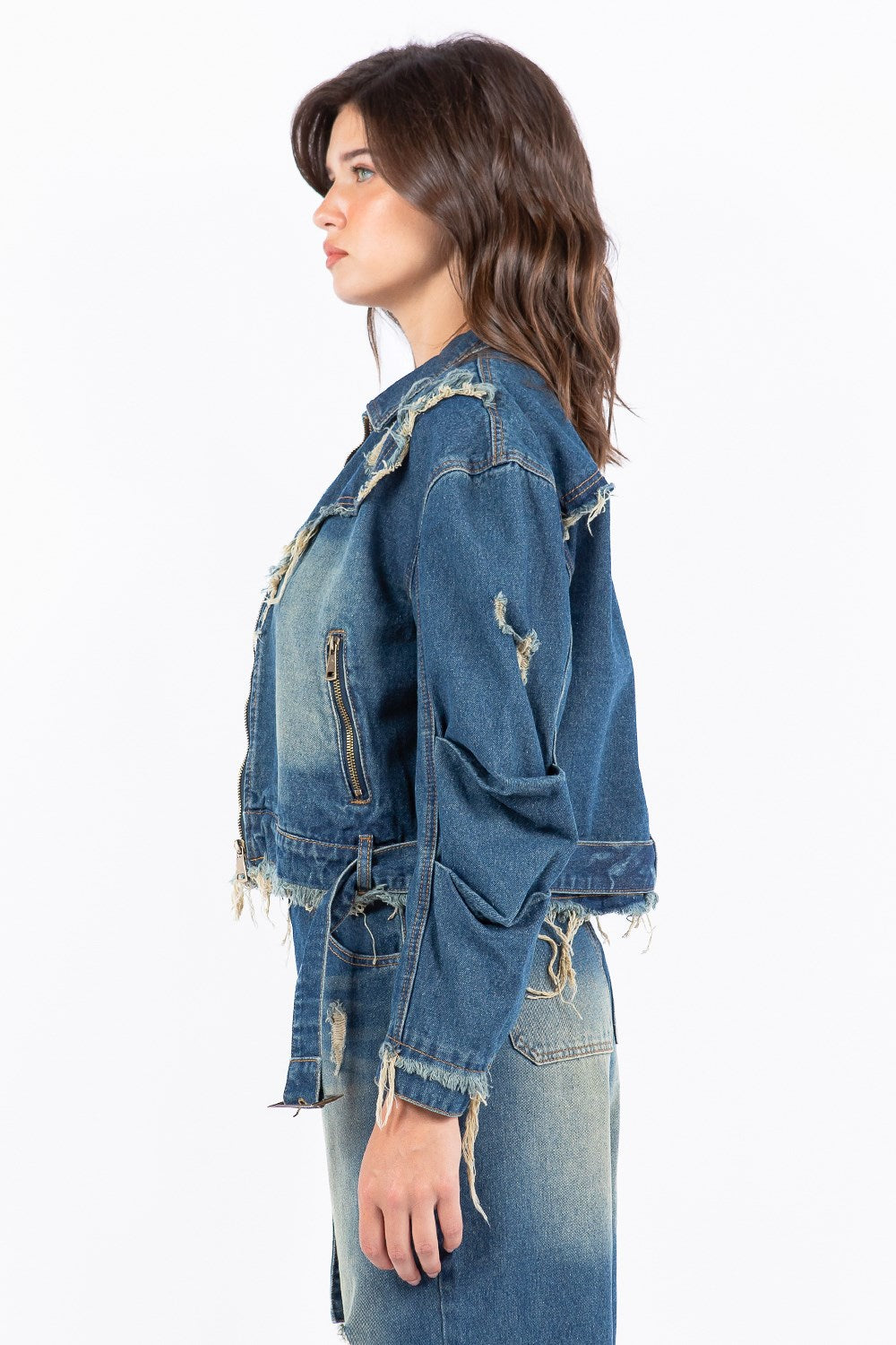 Woman wearing a blue medium wash distressed denim jacket with pockets on a white background