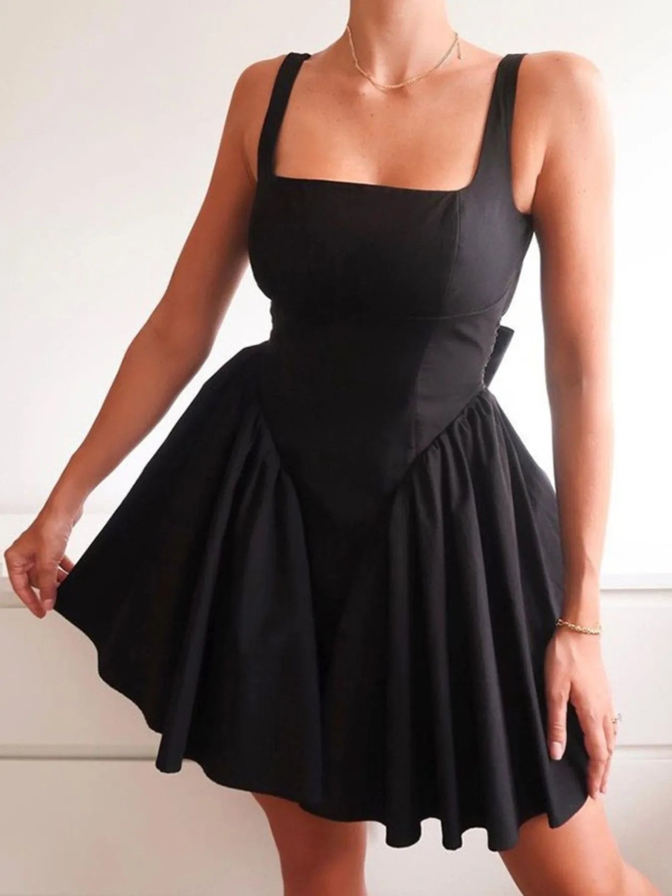 Model wearing black square neck open-back mini dress front view