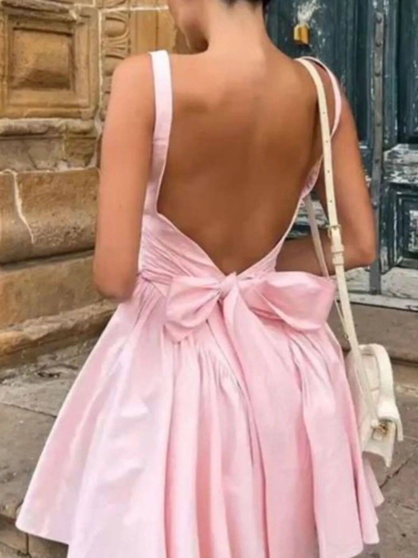Model wearing pink square neck open-back mini dress back view with bow