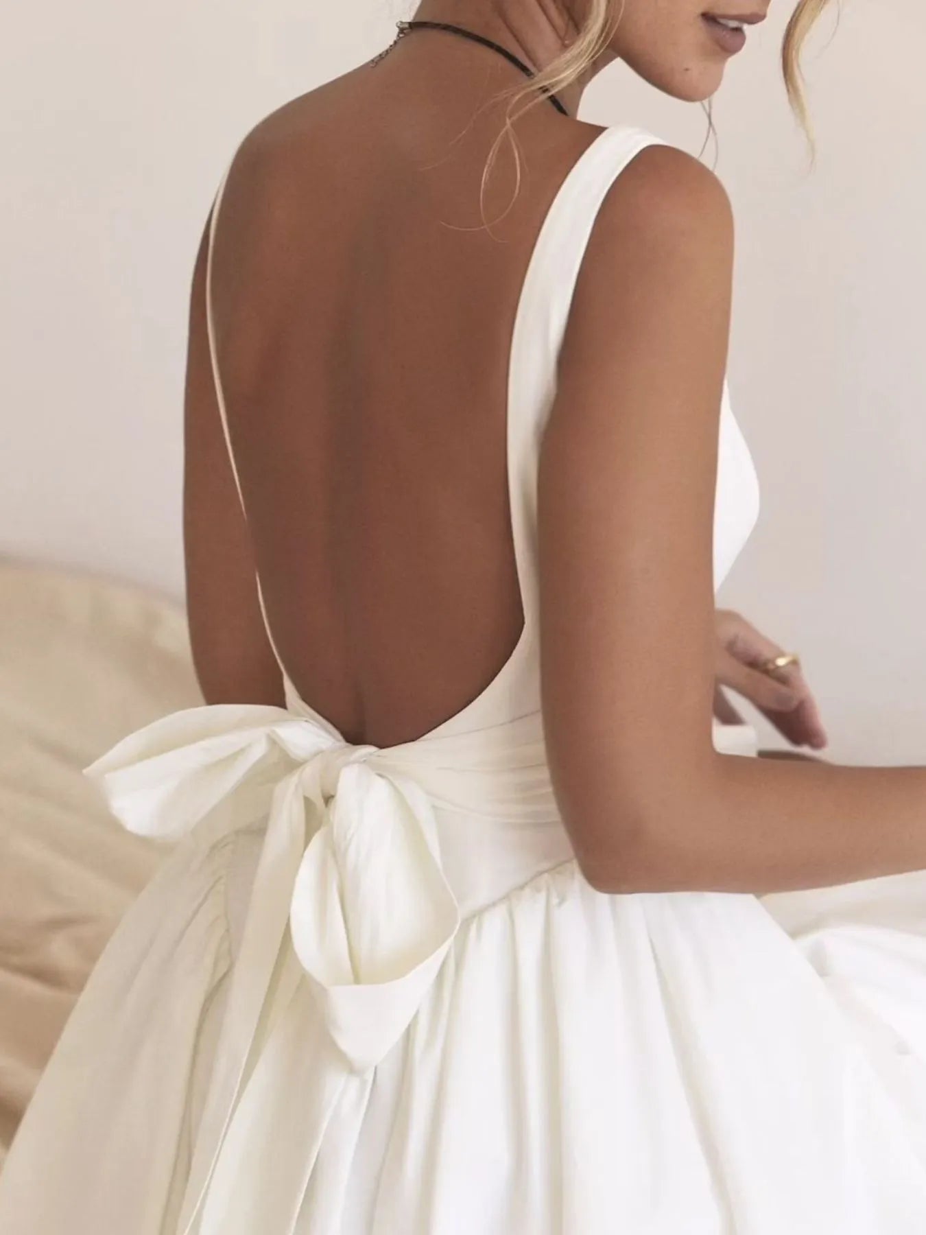 Back view of backless Square Neck Mini Dress in white with a bow on model