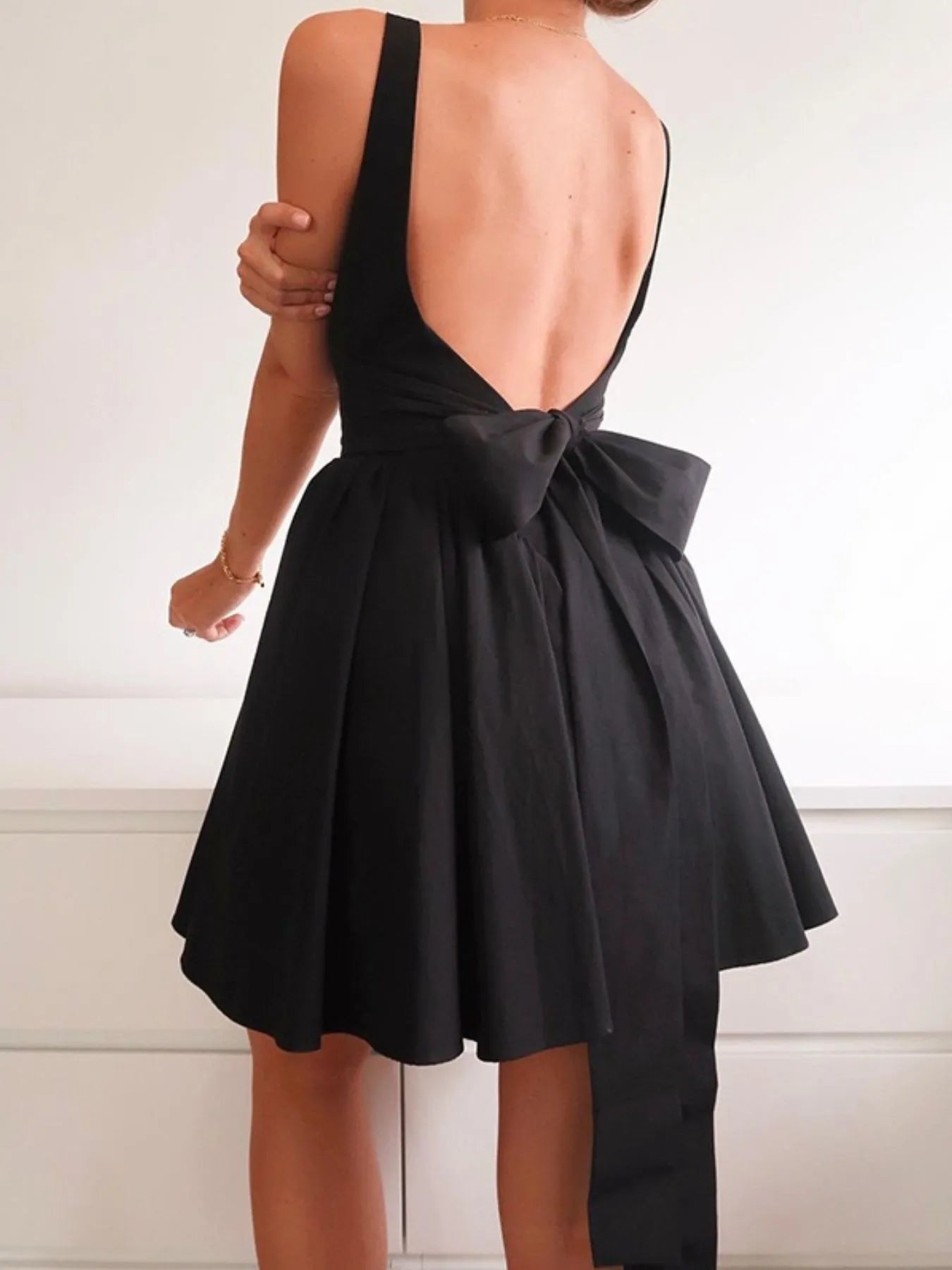 Model wearing black square neck open-back mini dress back view