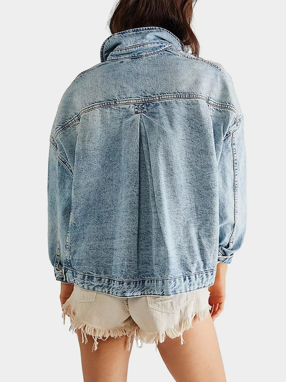 Back view of light blue denim jacket worn by a a woman on a white background