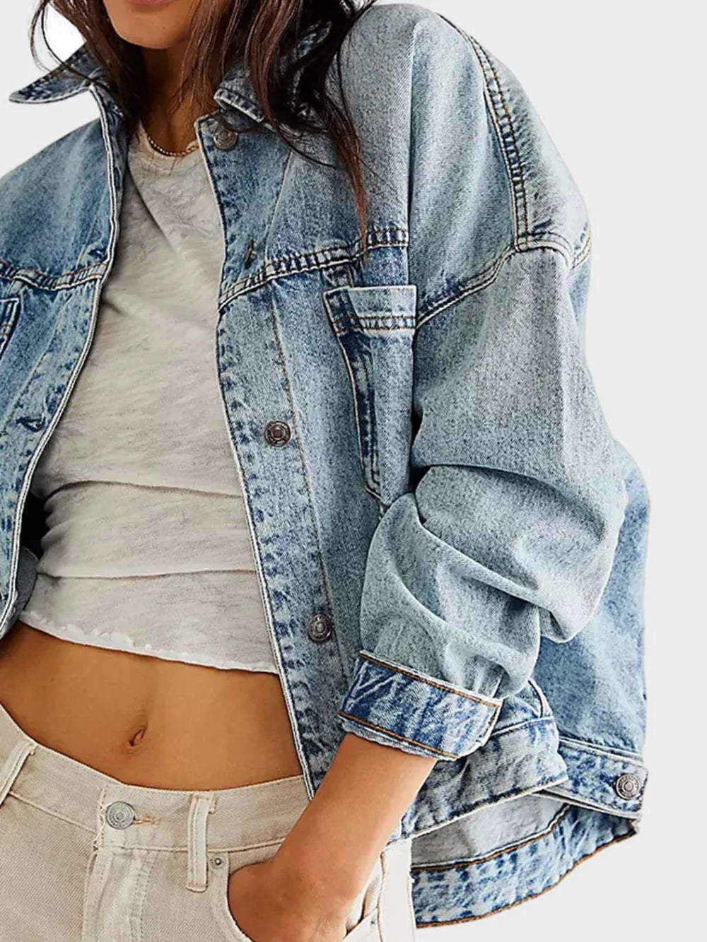 Woman wearing a light blue denim jacket with button front and pockets over a gray top on a white background