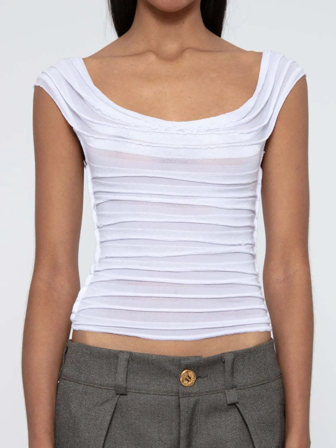 White sleeveless ruched top worn by a woman on a plain background