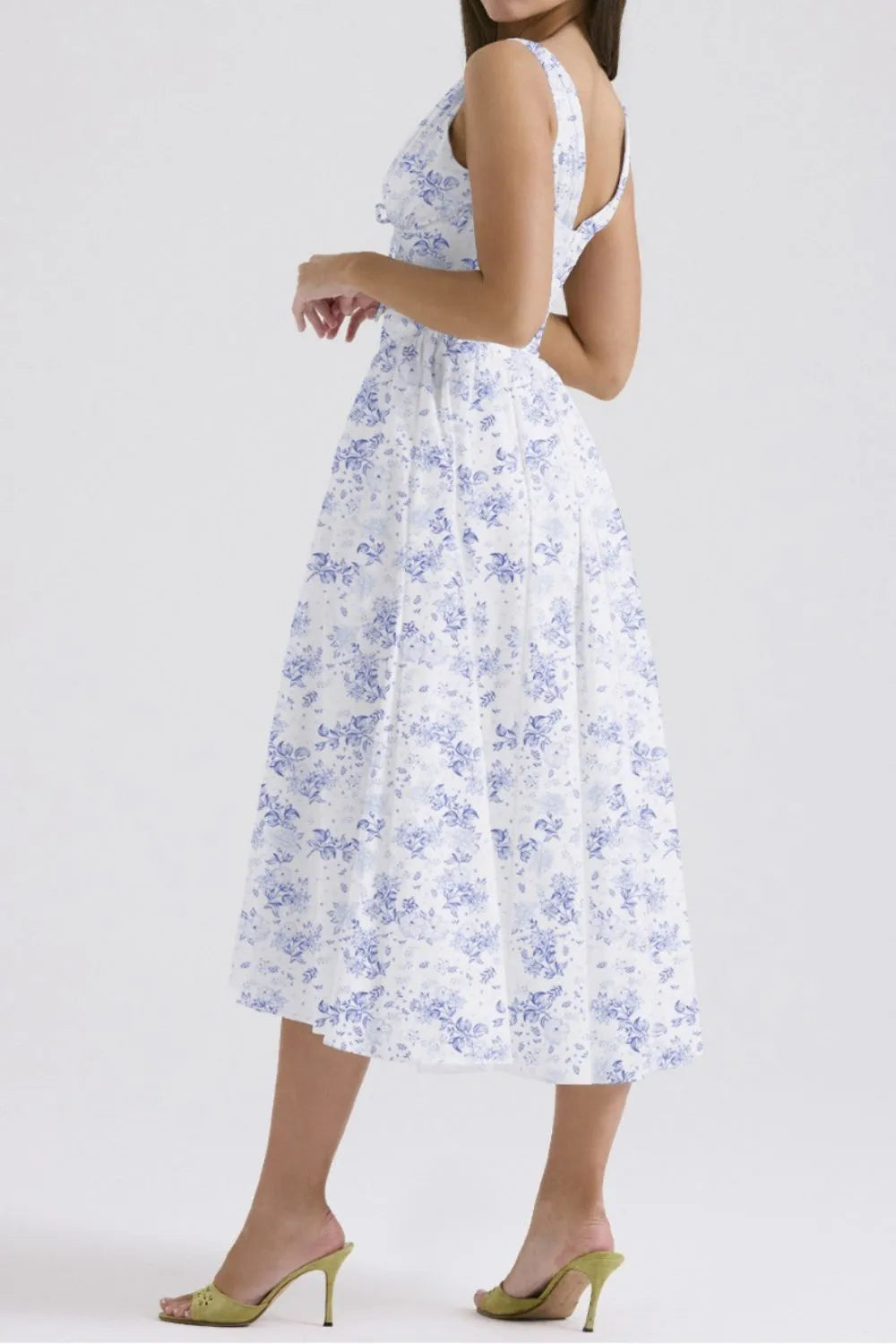 Woman wearing a white midi dress with blue floral print on a white background
