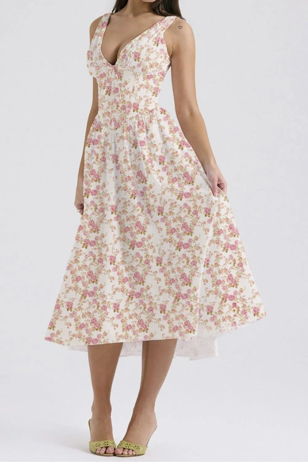 Woman wearing a floral white and pink sleeveless midi dress on a white background