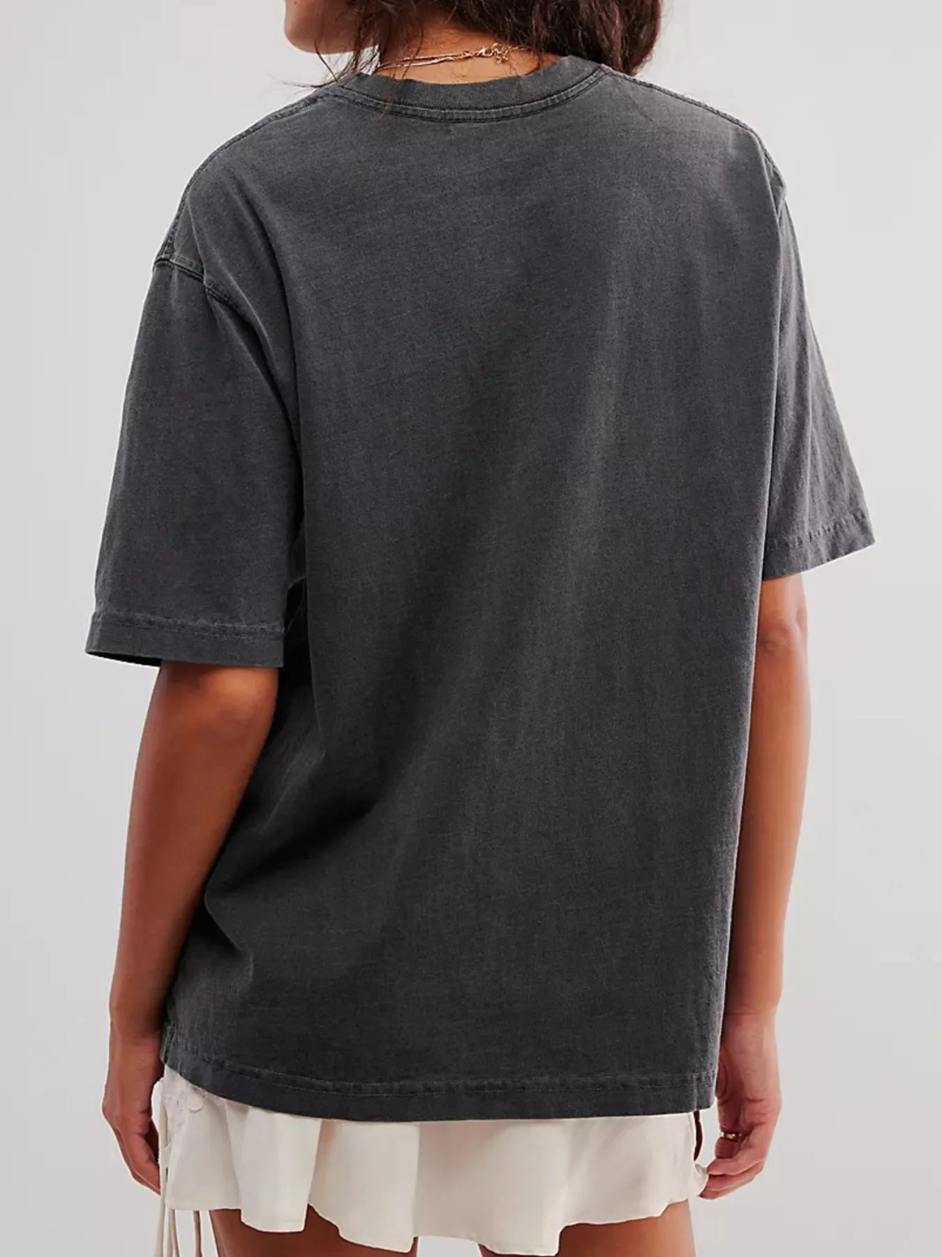 Back view of woman wearing a dark gray short sleeve loose t-shirt on a plain background