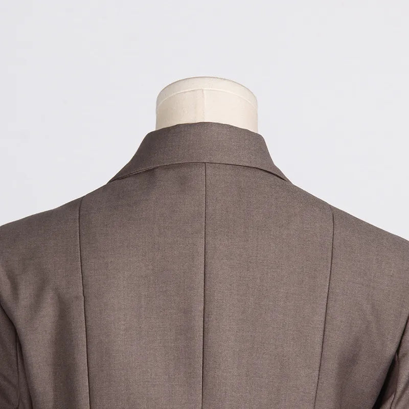Close up of back detail of a luxury fashion inspired brown hollow-out cinched waist irregular long sleeve blazer on a mannequin