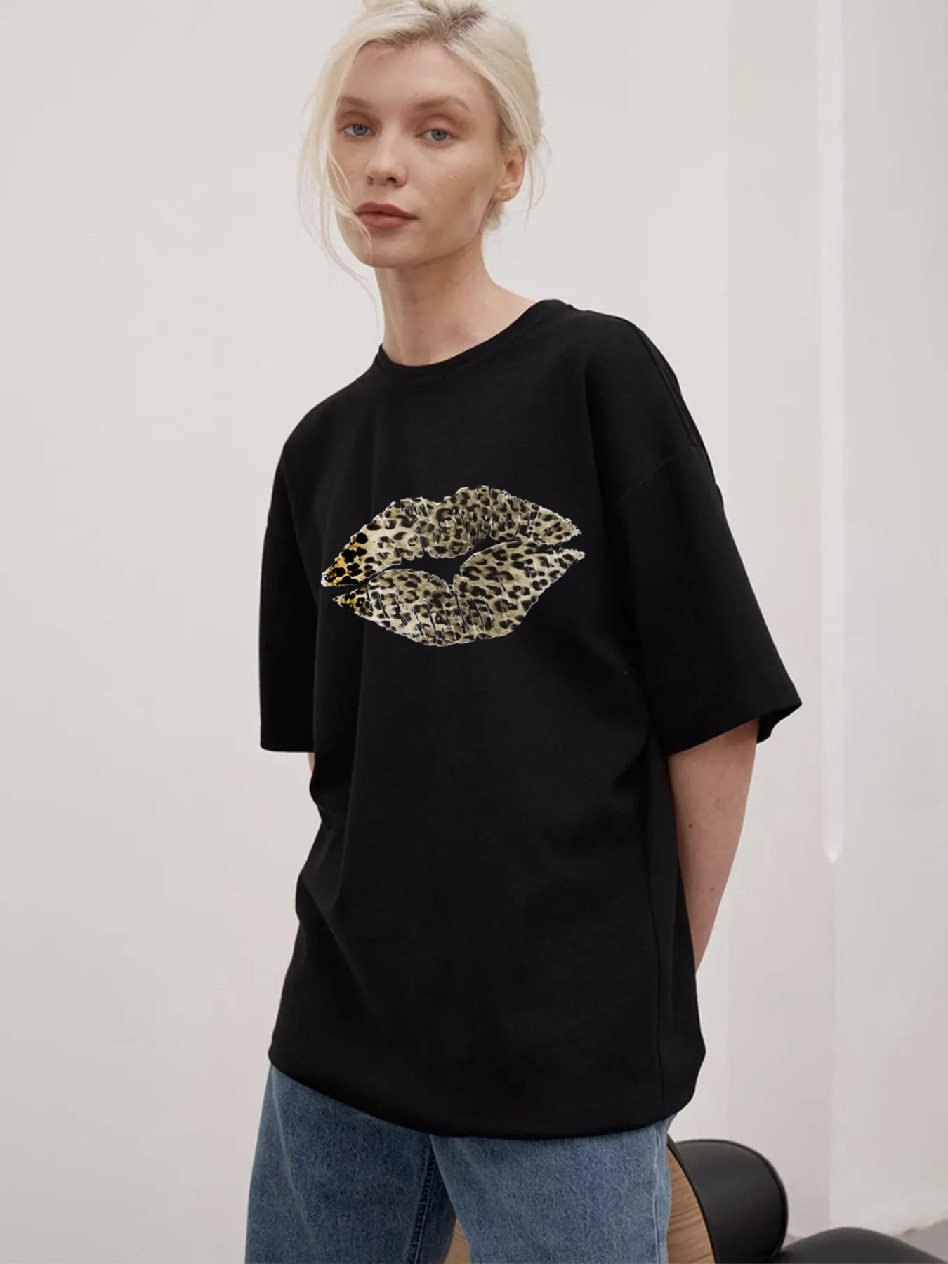 Model wearing black oversized t-shirt with leopard lip graphic and round neckline front view with jeans