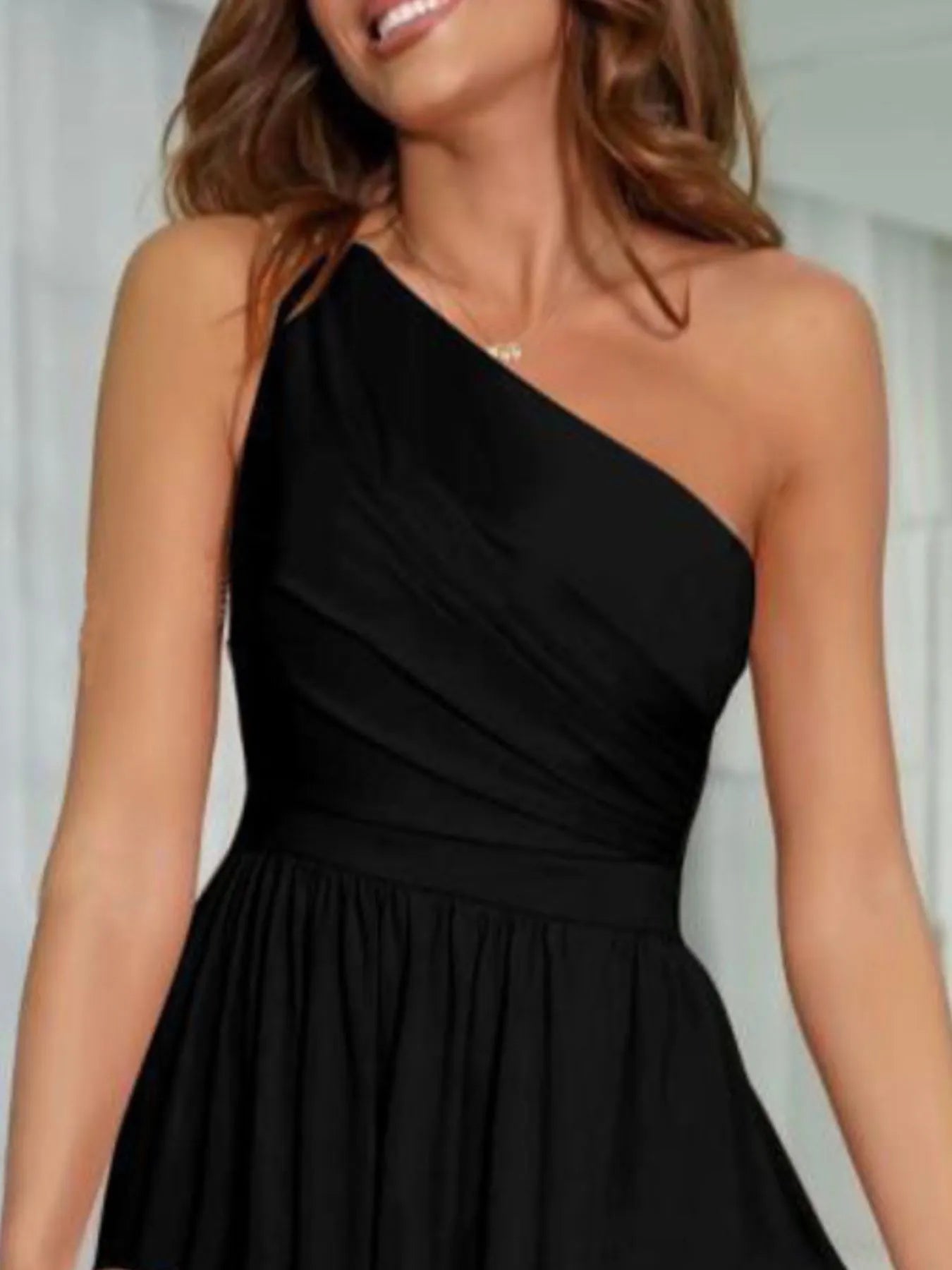 Close up of one shoulder neckline of evening maxi dress on a woman on a neutral background