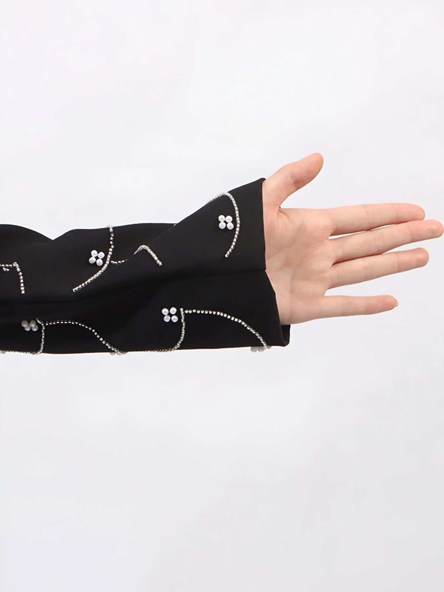 Black sleeve with white pearl details on a white background