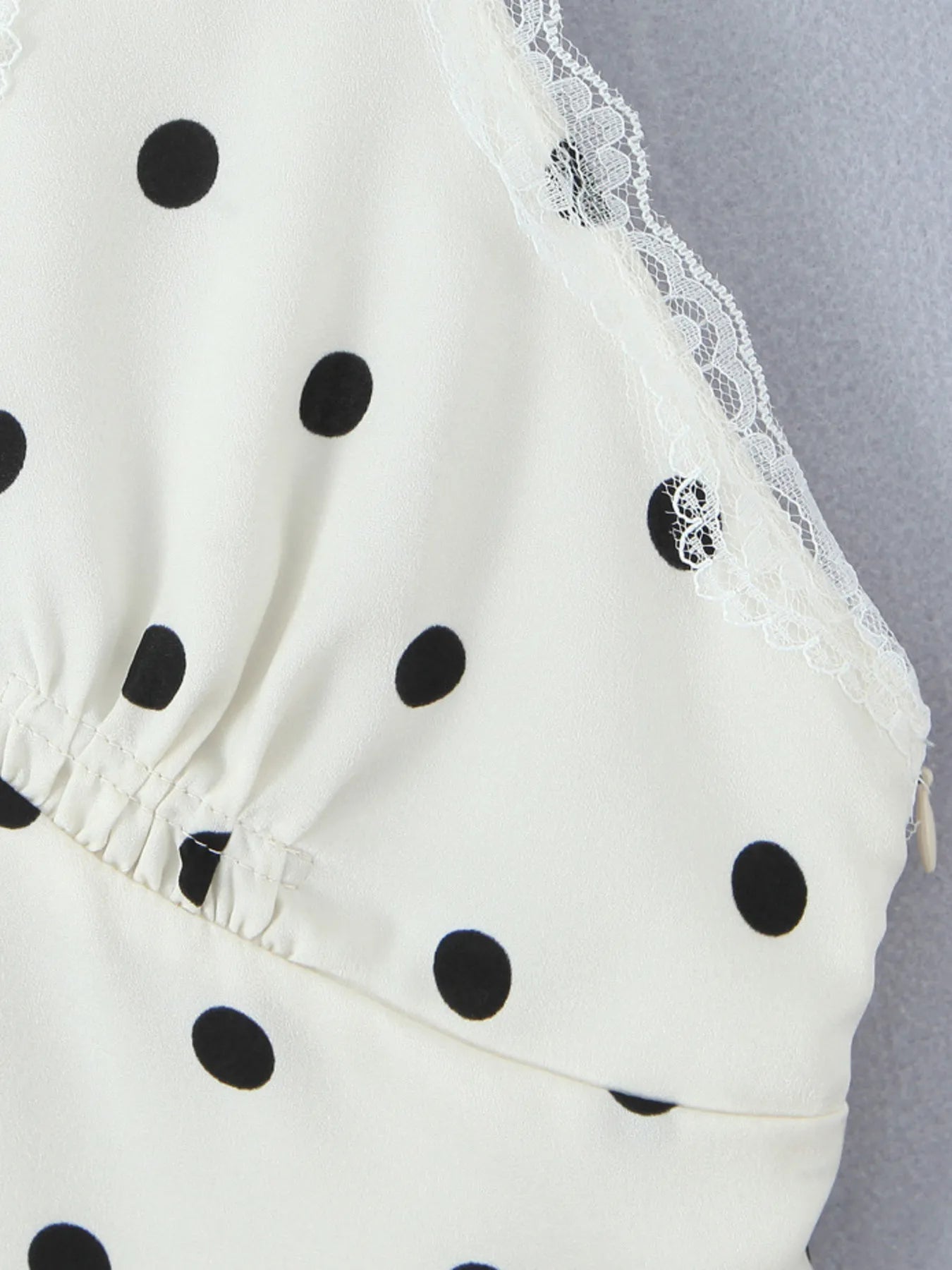 Close-up of polka dot fabric and lace trim of polka dot halter mini dress