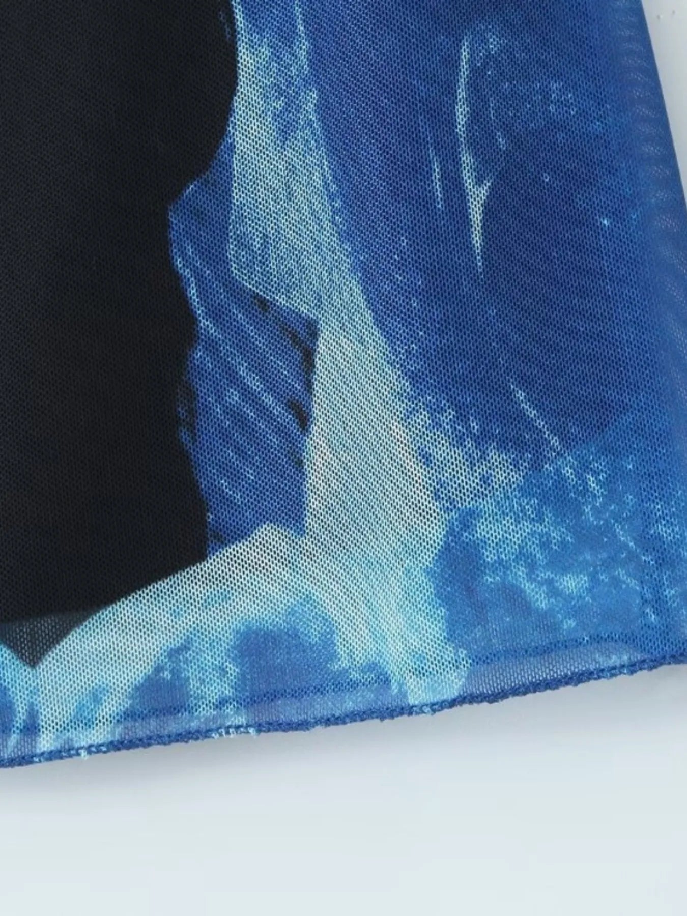 Close-up of blue floral printed mini cami dress hem on a white background