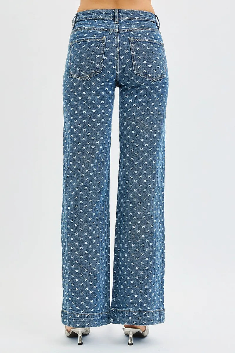 Back view of woman wearing blue bow patterned high waisted wide leg jeans worn on a white background