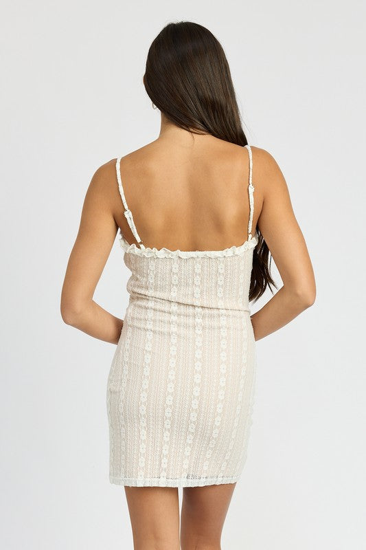 Woman wearing a white lace mini dress with ruffle trim v-neckline and adjustable straps on a white background back view