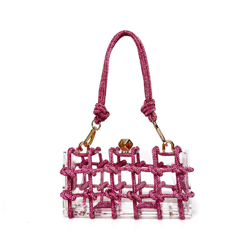 A shiny rhinestone-encrusted bright pink acrylic clear handbag in a square shape with a single shoulder strap and gold-colored hardware.