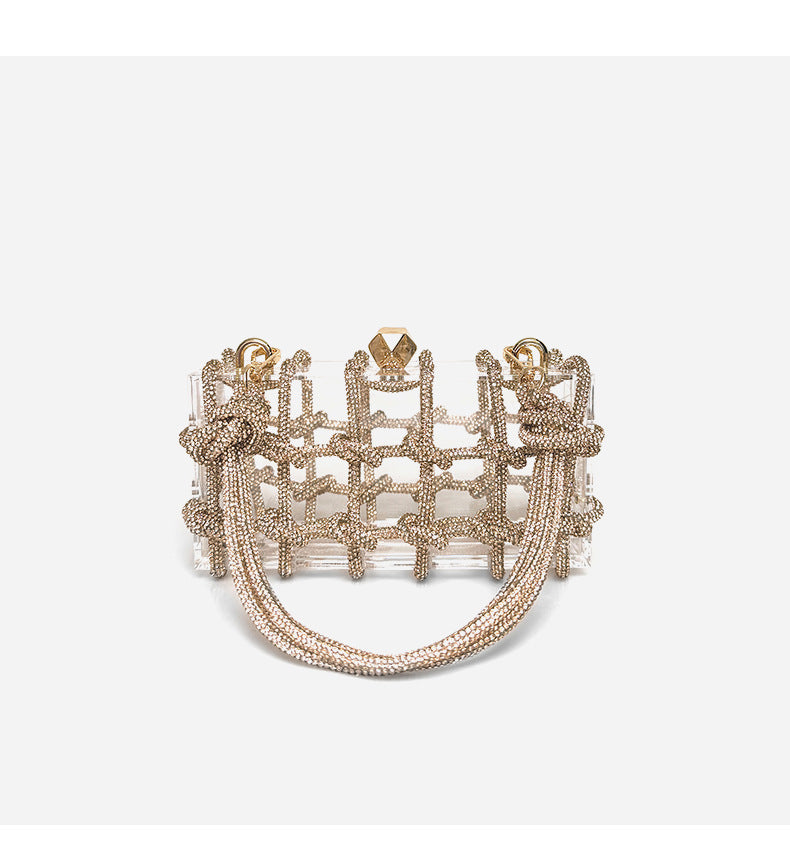 A shiny rhinestone-encrusted champagne acrylic handbag in a square shape with a single shoulder strap and gold-colored hardware.
