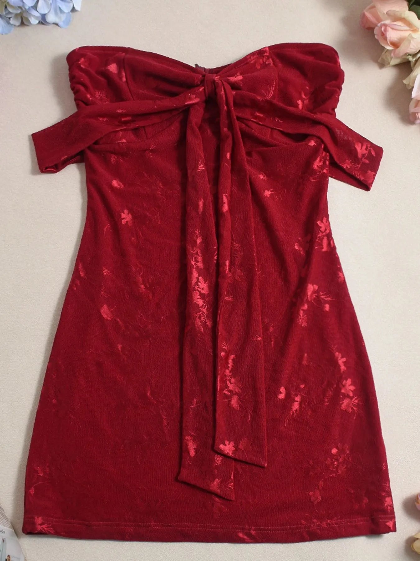 Red Sweetheart Neck Draped Off-Shoulder Bodycon mini Dress on a beige background