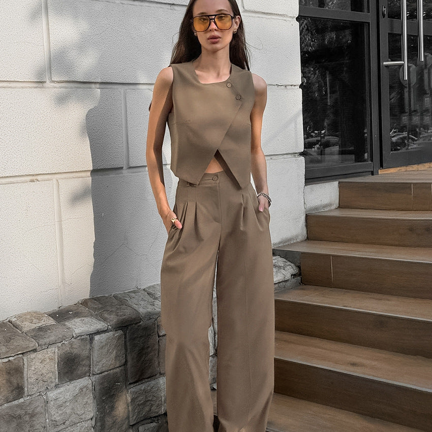 Woman in a brown two piece vest and pant suit set outfit standing on near outdoor steps.
