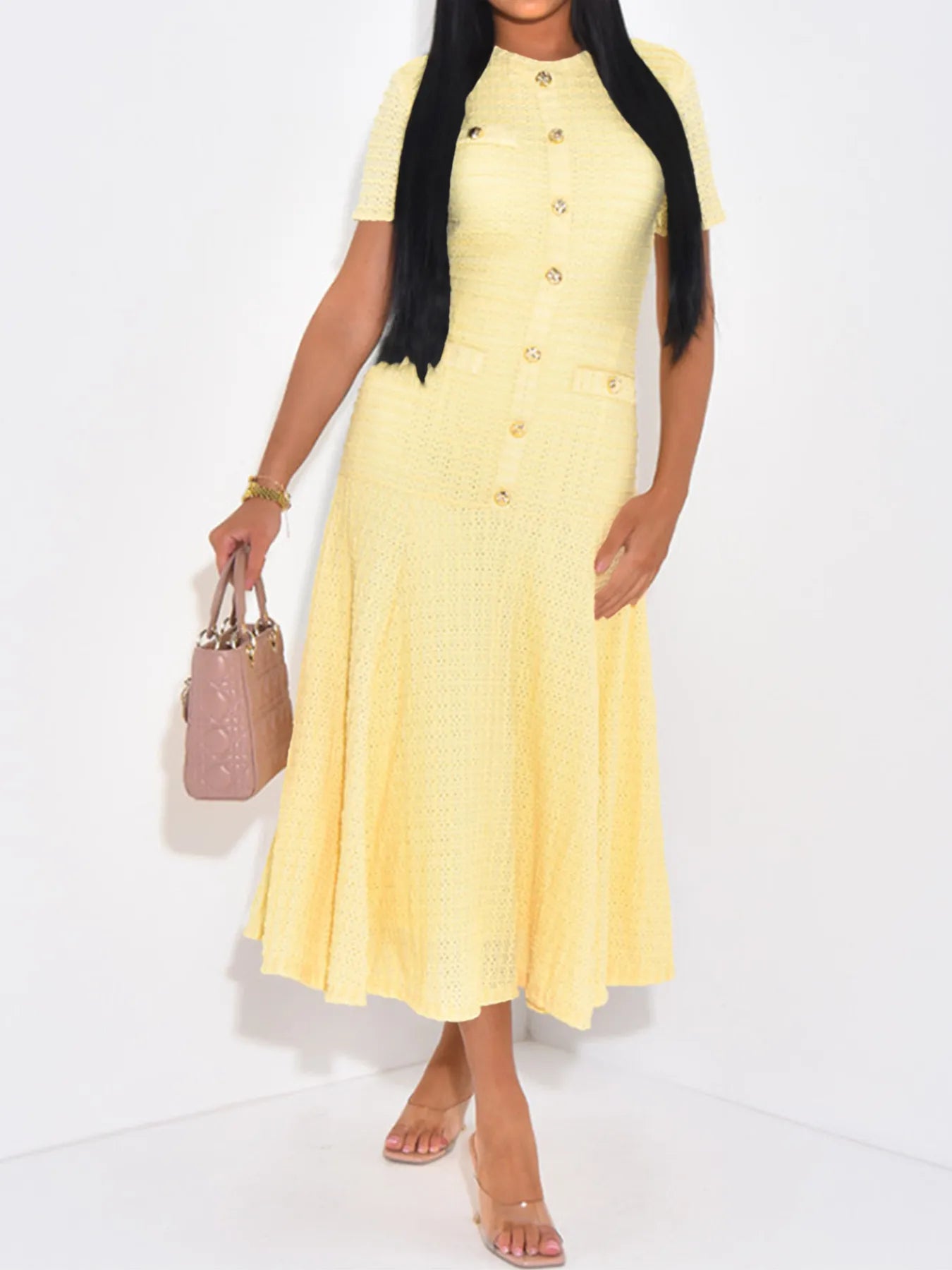 Front view of Woman wearing a butter yellow textured knit midi short sleeve dress holding a pink handbag on a white background