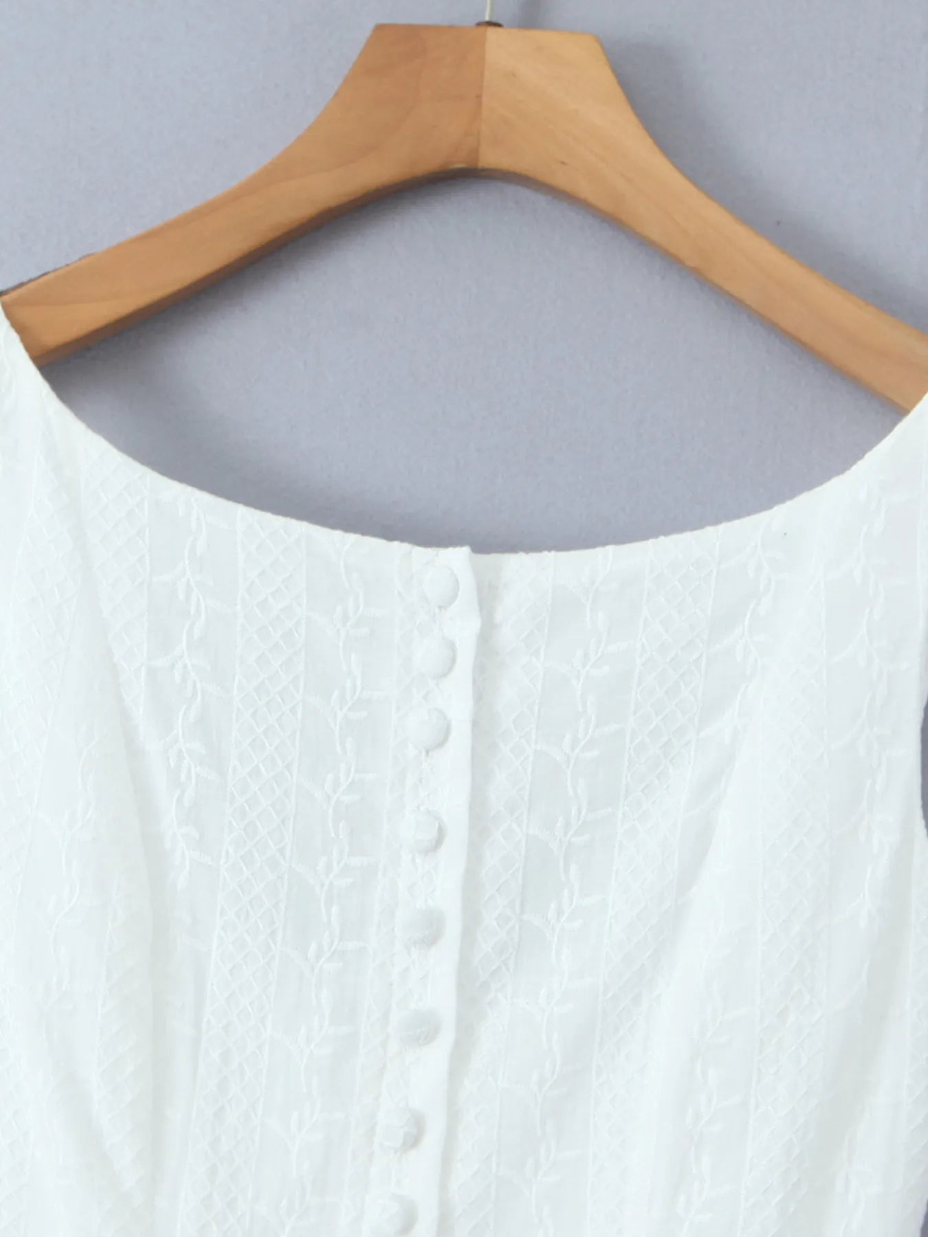Close-up of lace mini dress in white neckline and fabric texture on hanger