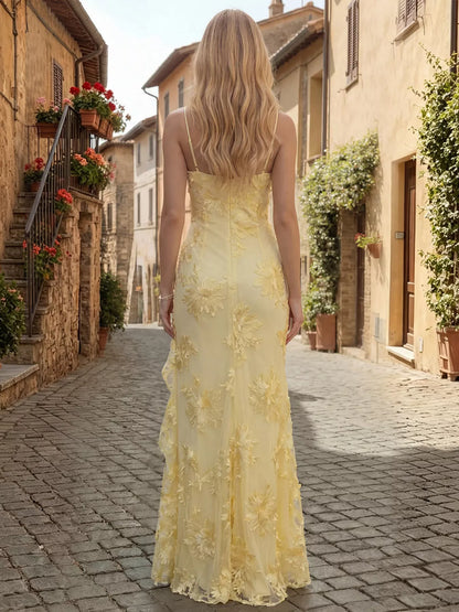 Back view of woman in a long butter yellow floral lace dress  with slit  for wedding or formal wear standing on a cobblestone street with Italian architecture.