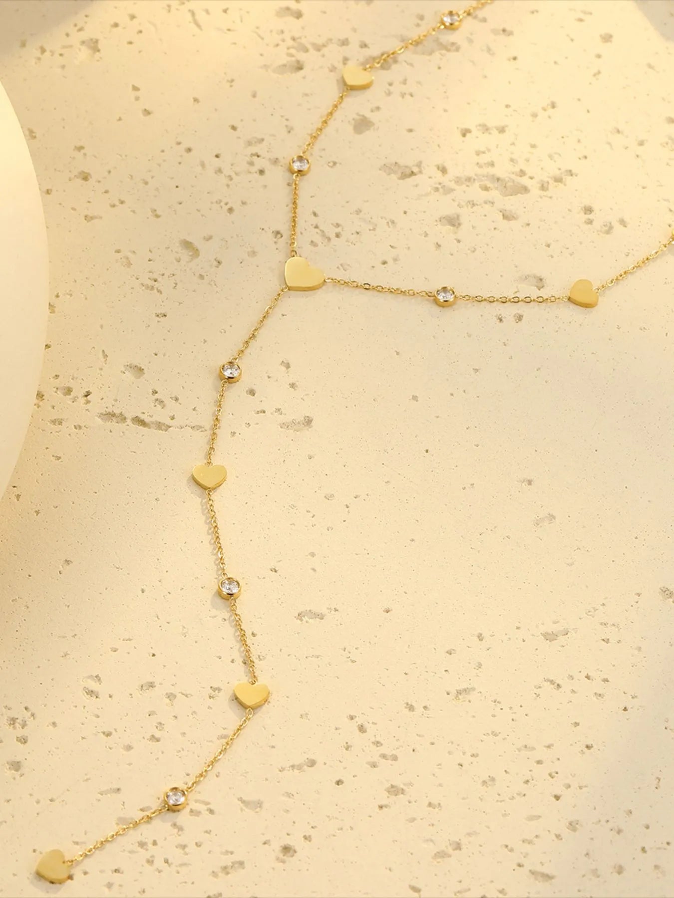 18K gold plated heart zircon necklace with crystal charm on cream surface