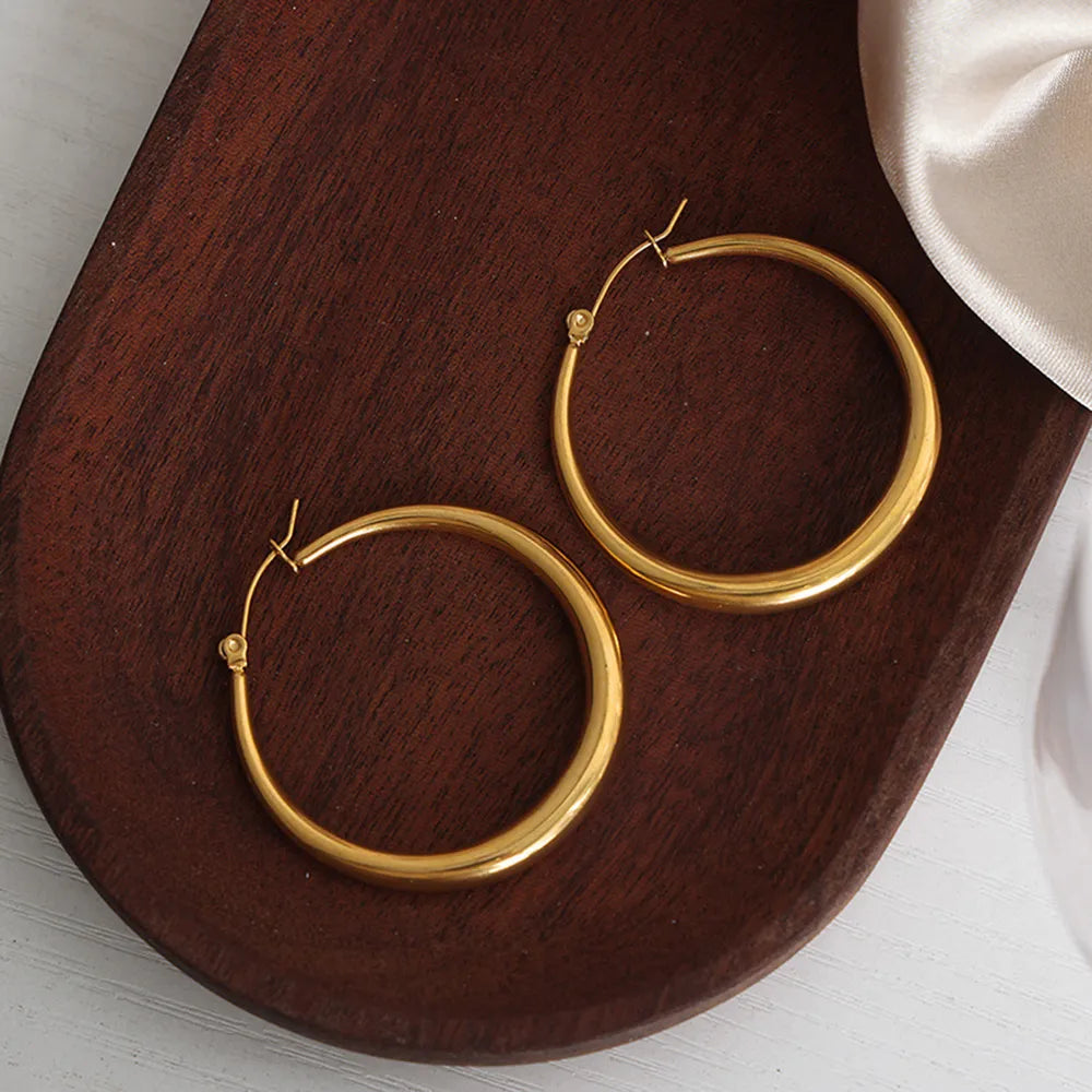 Medium gold plated hoops for women – minimalist design on a wooden  jewelry dish 