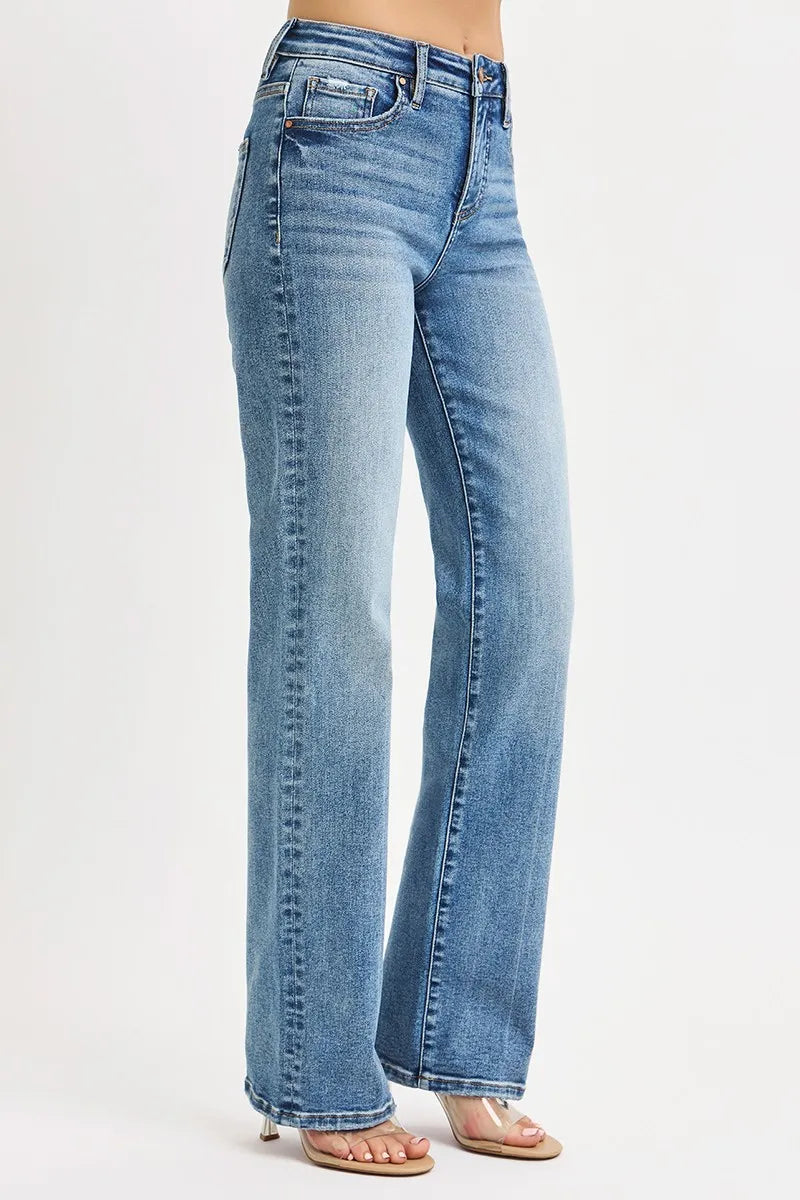 Side view of woman wearing stretchy medium wash blue high rise tummy control straight leg jeans on a white background
