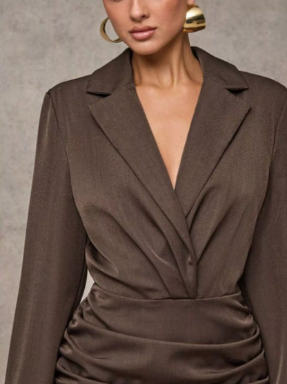 Brown blazer style ruffled mini dress with long sleeves on a neutral background on a woman  close up front view