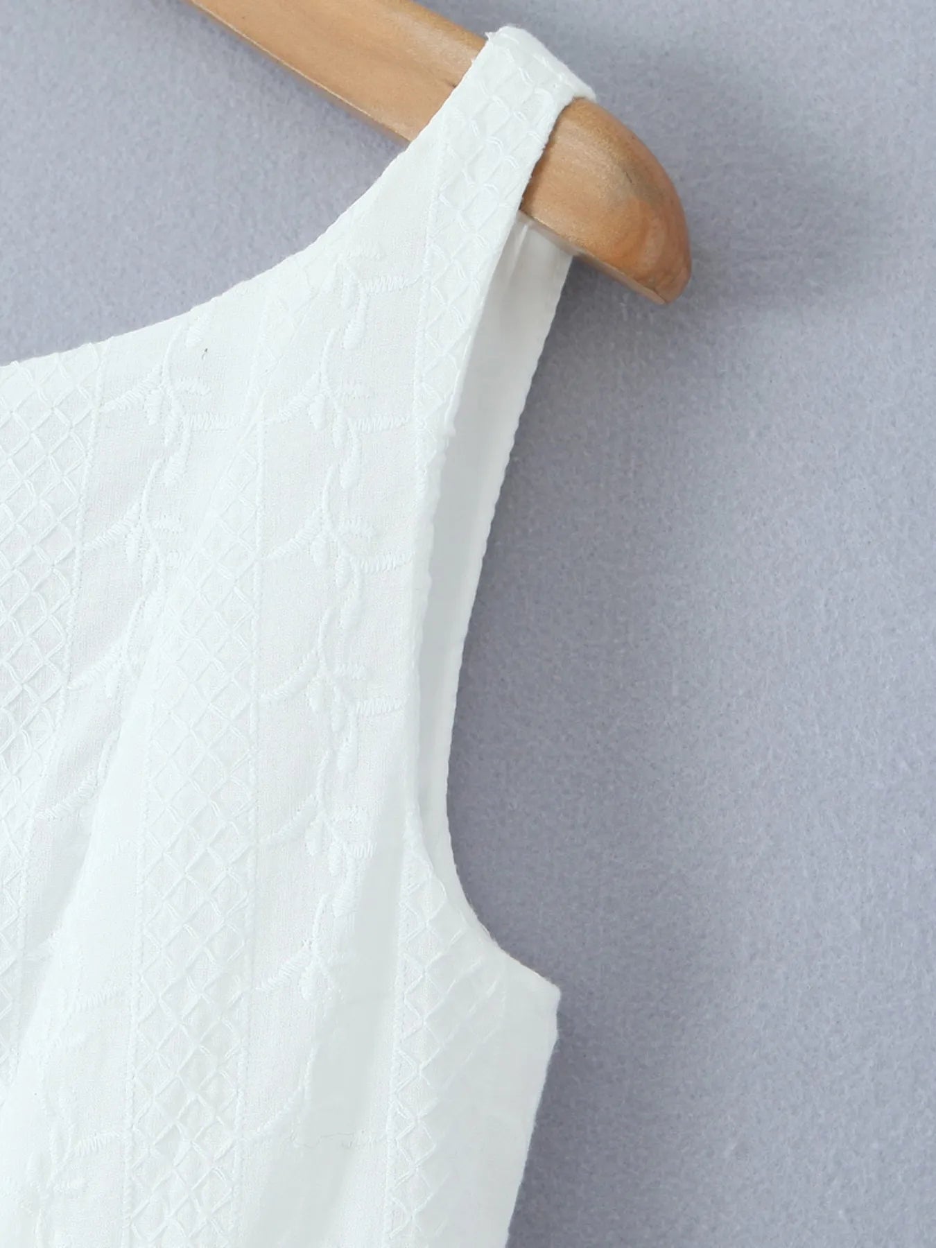 Close-up of lace mini dress in white sleeveless arm and fabric texture on hanger