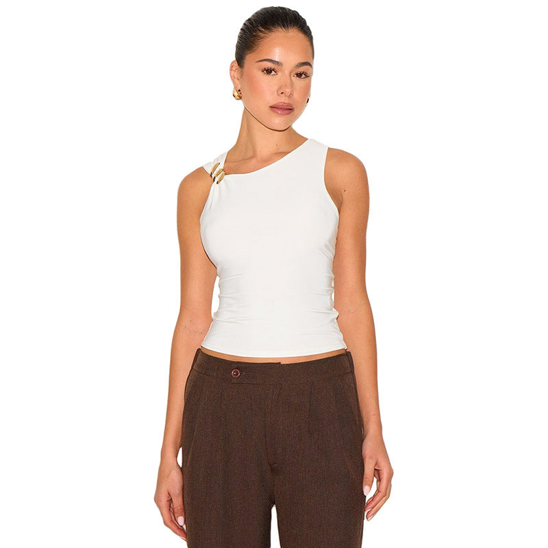 Woman wearing a white sleeveless top with gold clasp and brown pants on a white background