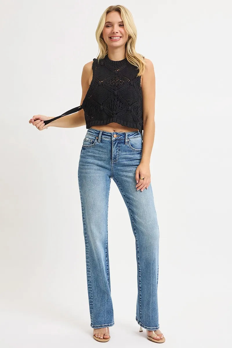 model posing in black knit top and medium wash blue high rise tummy control straight leg jeans on a white background