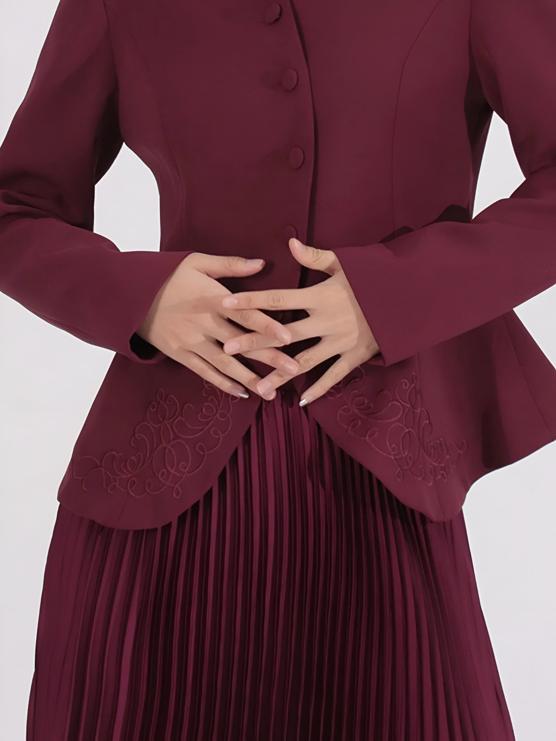 close up of embroidered suit jacket with a  pleated maxi skirt  on a white background