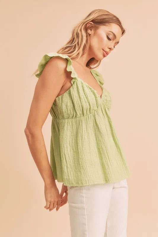 Model posingi in a  sweetheart neck ruffled strap top in fitted flowy silhouette side view
