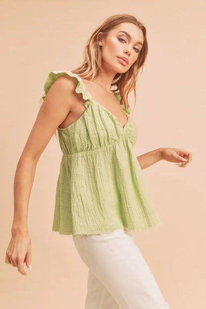 Model wearing sweetheart neck ruffled strap top in fitted flowy silhouette side view