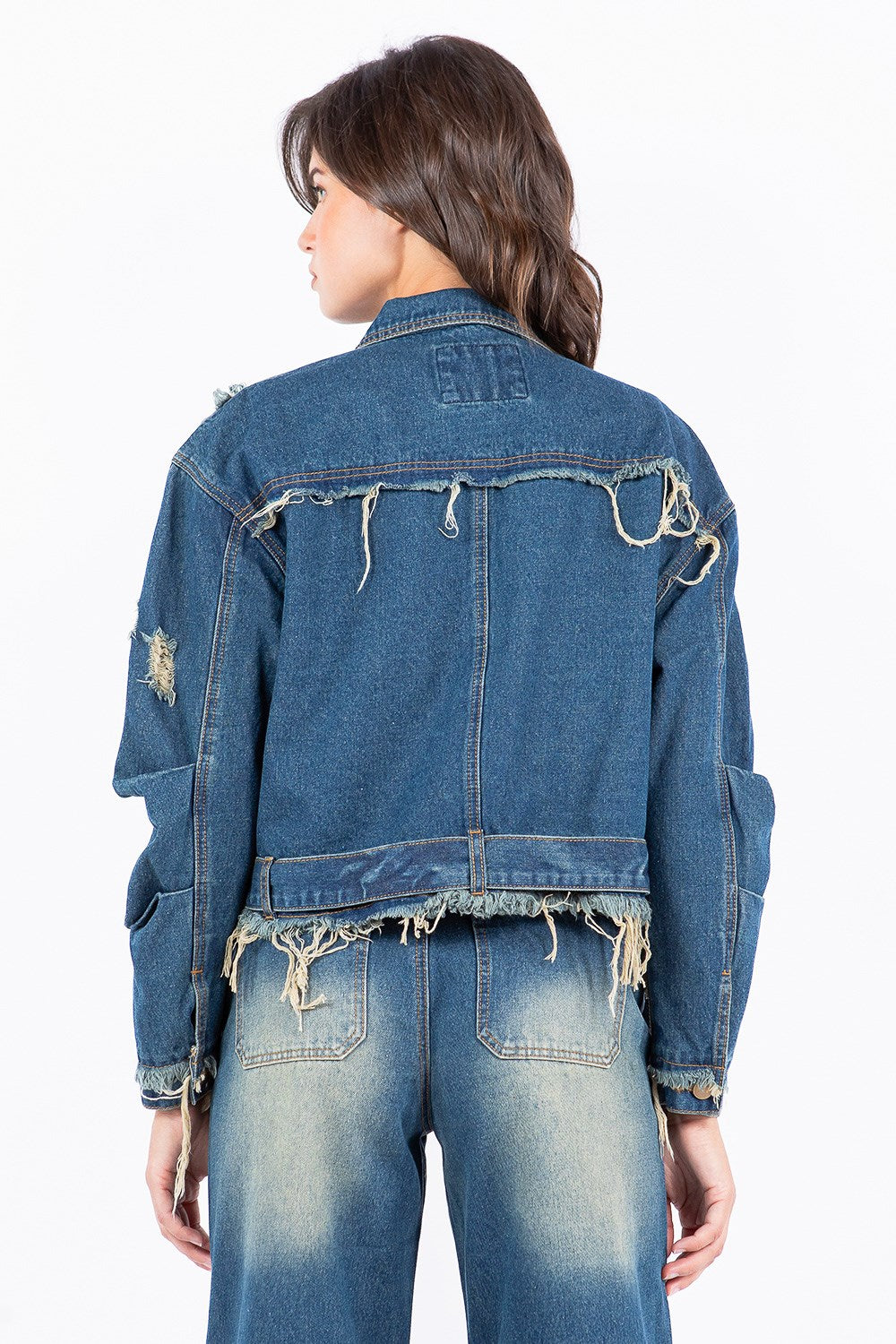 Woman in a blue  distressed frayed street style denim jacket and jeans on a white background