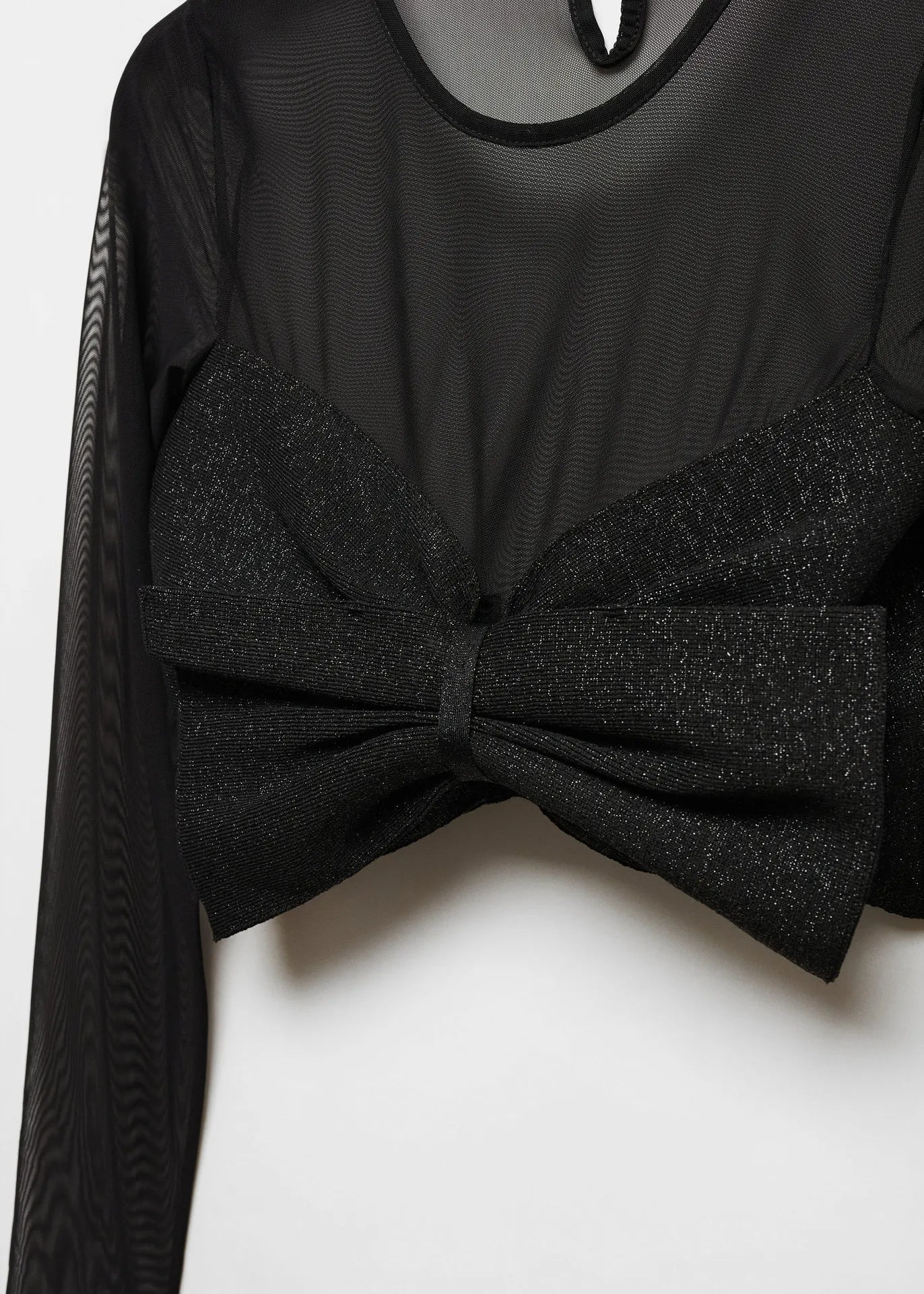 Black sheer long-sleeve top with large glittery bow at the front, creating a cropped style.