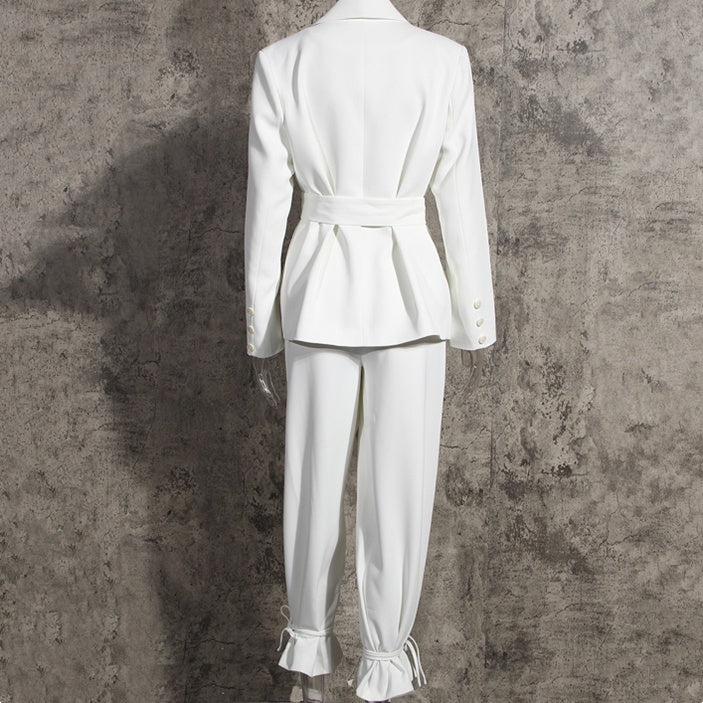 Back view of a high-fashion women’s white tailored blazer pants suit set on a mannequin on a gray background