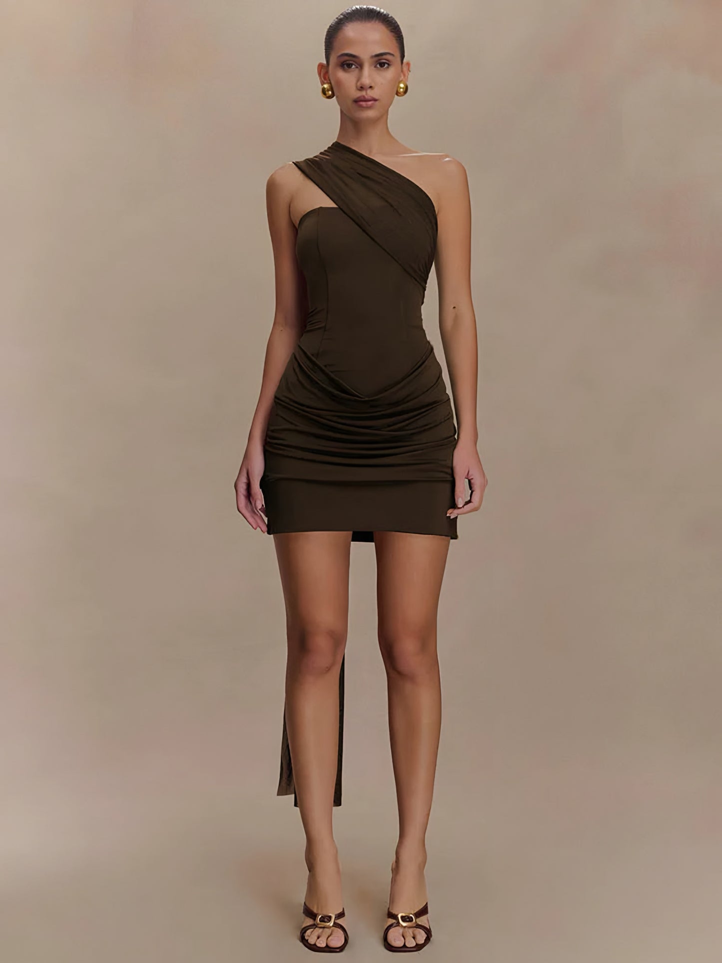 Woman wearing a brown draped one-shoulder mini dress on a beige background front view