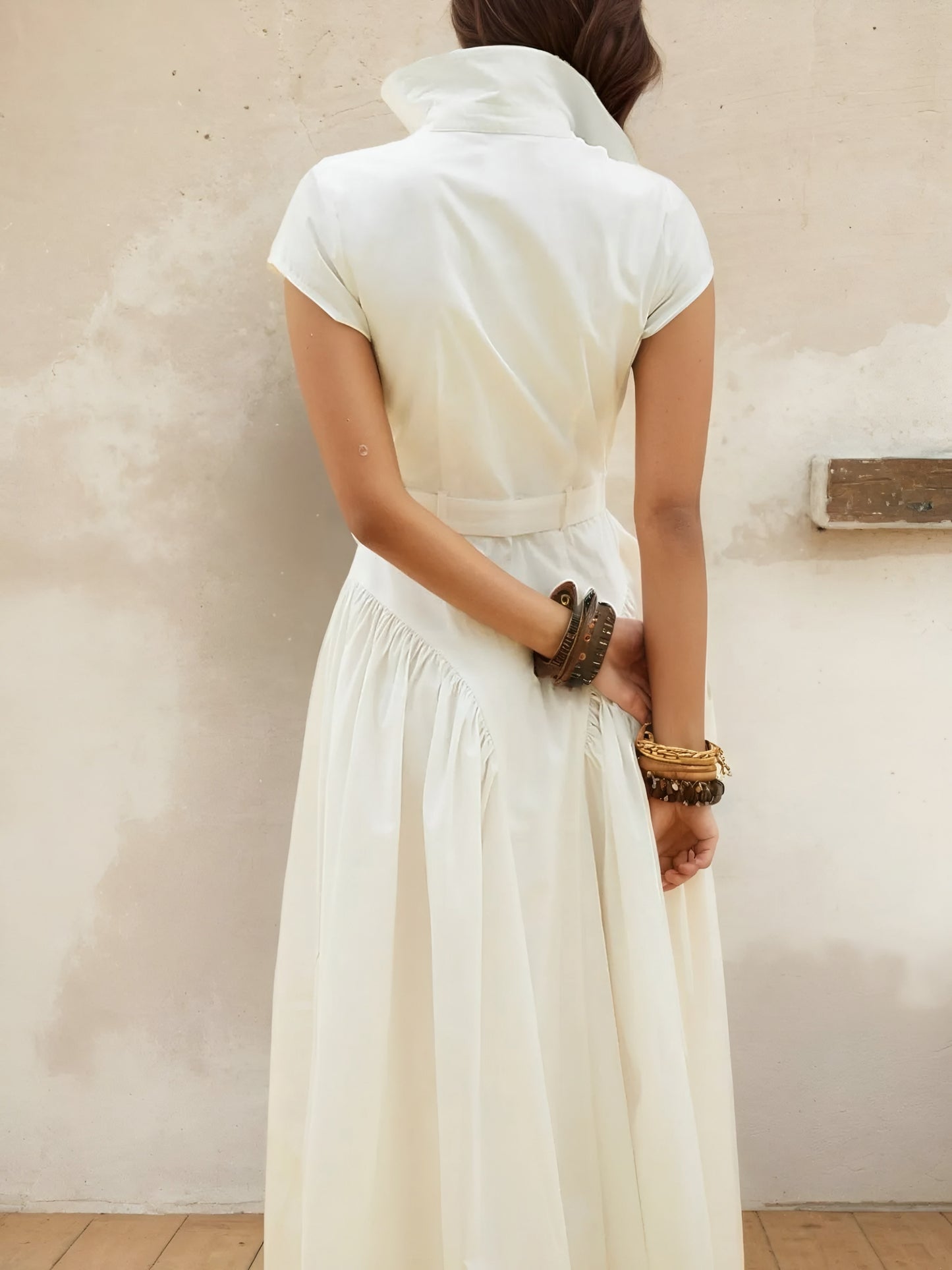 Back view of woman  wearing a white cap sleeve belted midi resort style dress with a neutral background