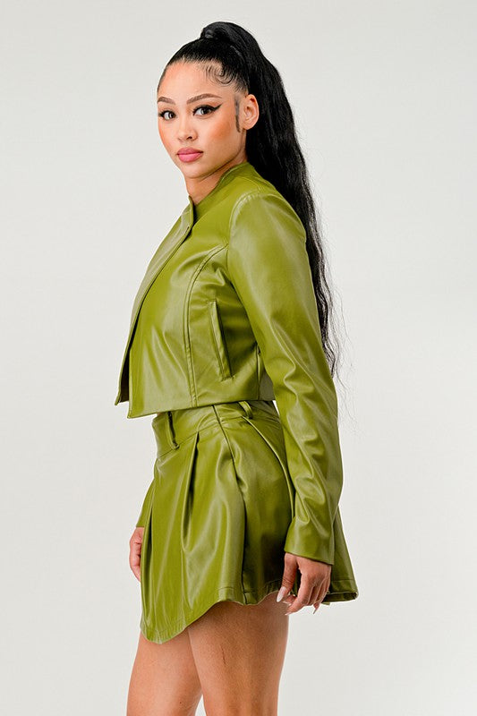 Close up of side view of woman wearing a green button-up PU leather cropped jacket with mini skirt