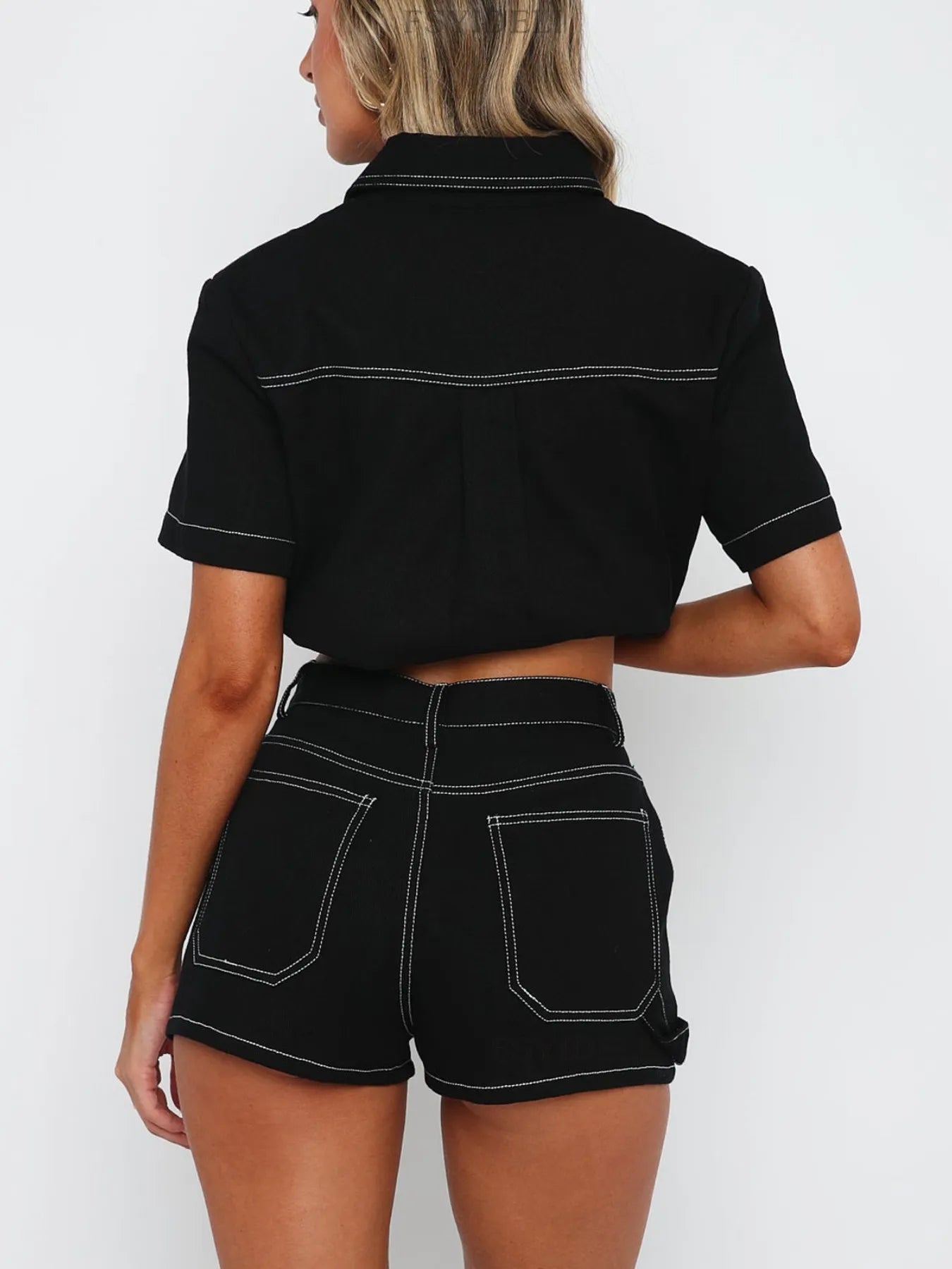 Model wearing matching button-up denim top and shorts set in black back view