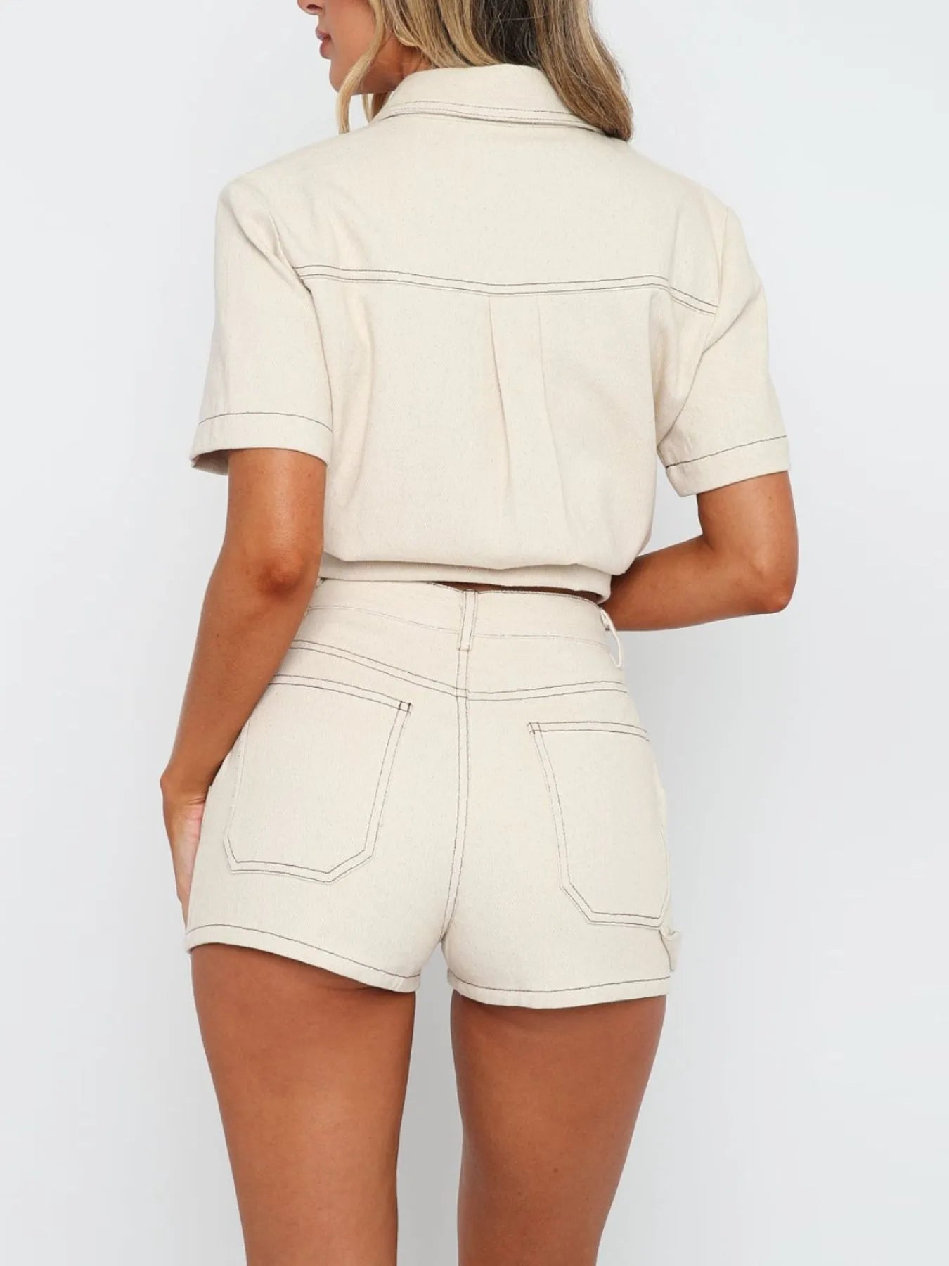 Model wearing matching button-up denim top and shorts set in white back view