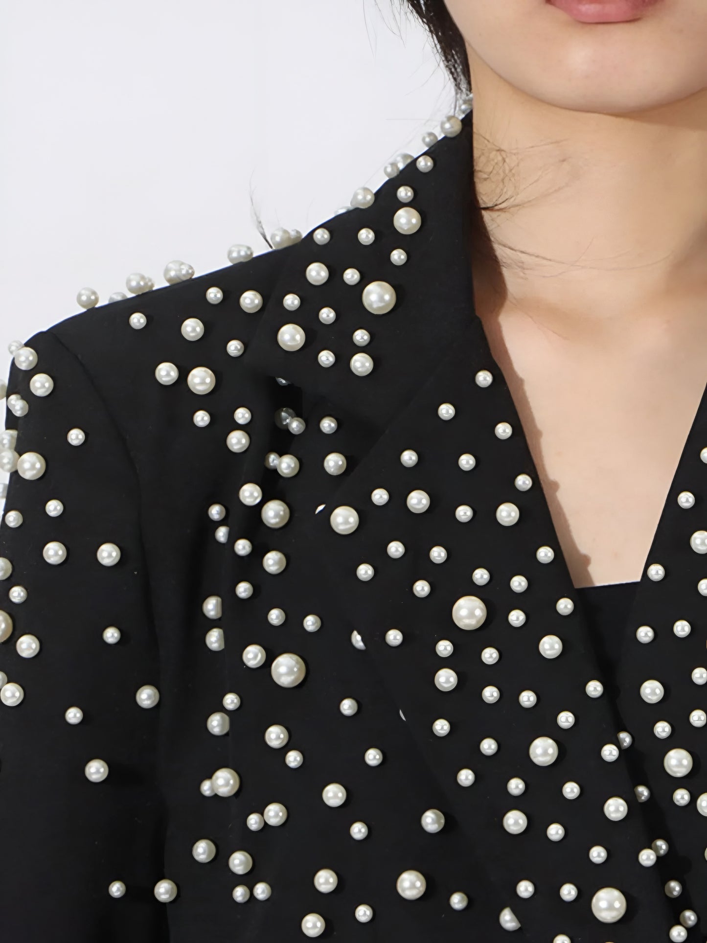 Black couture-inspired  high fashion luxuryblazer with pearl embellishments on a white background