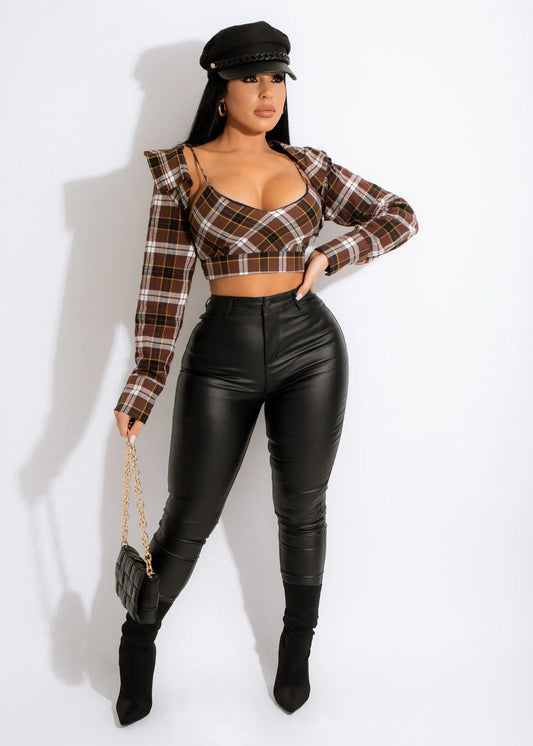 Woman wearing a plaid top and black stretch body fitting leather skinny leg pants on a white background front view