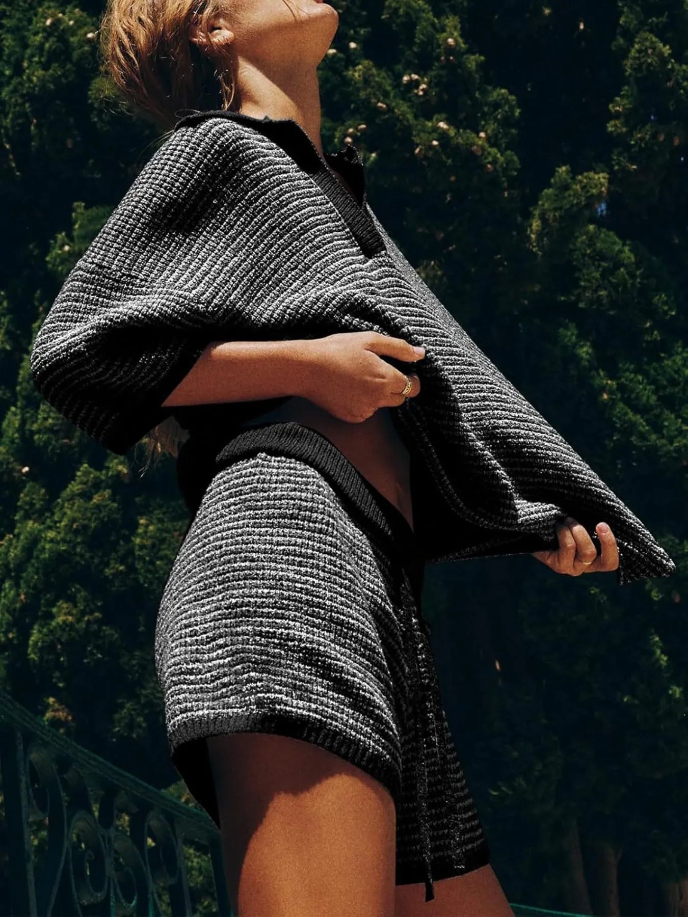  side view of woman wearing a black collared contrast striped knit top and matching shorts co-ord set.
