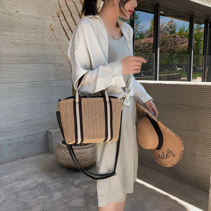 Woman holding a straw woven beach bag and straw hat in an outdoor setting