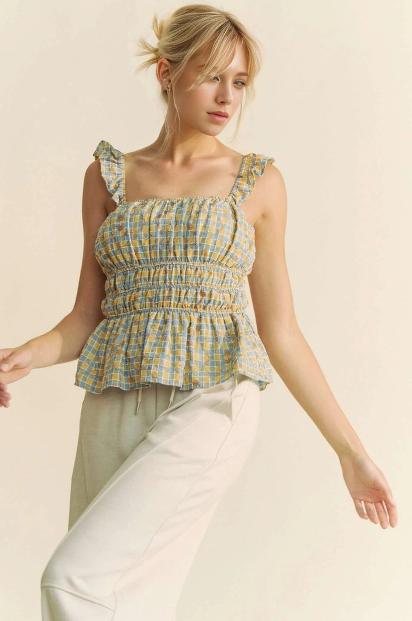 Model wearing plaid smocked top with ruffle straps 
